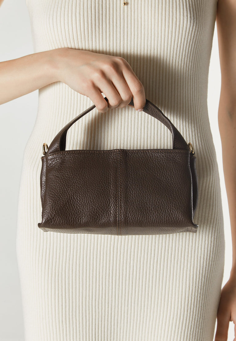 Women's dark brown handbag by Estro - presented in the model’s hand.