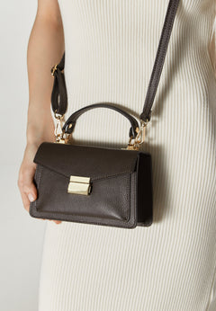 Women's small dark brown handbag made of premium Italian genuine leather by Estro  – presented on a model.