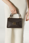 Women's small dark brown handbag - presented in the model’s hand.