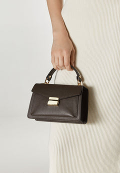 Women's small dark brown handbag made of premium Italian genuine leather - presented in the model’s hand.