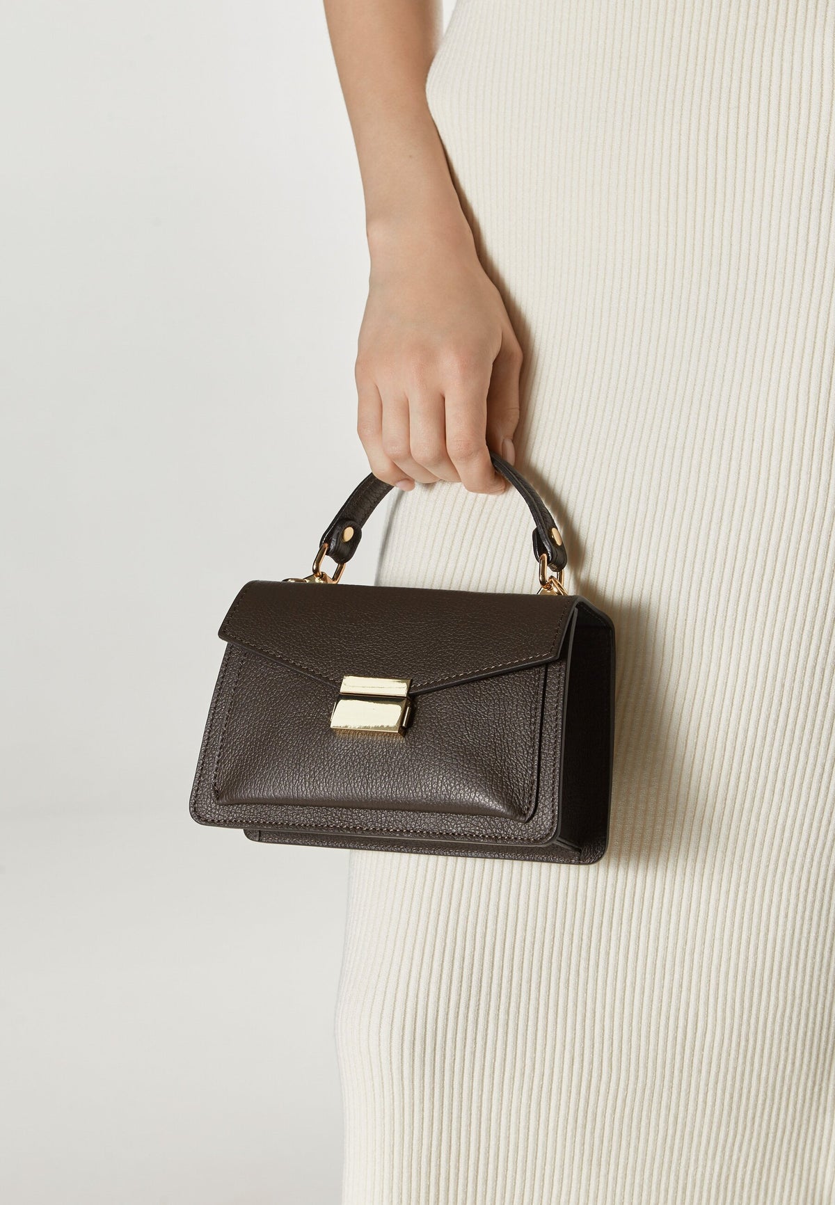 Women's small dark brown handbag made of premium Italian genuine leather - presented in the model’s hand.