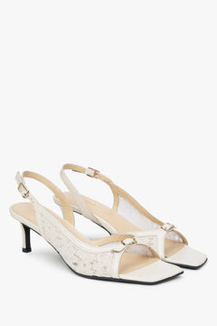 White slingback sandals with decorative lace and a heel.