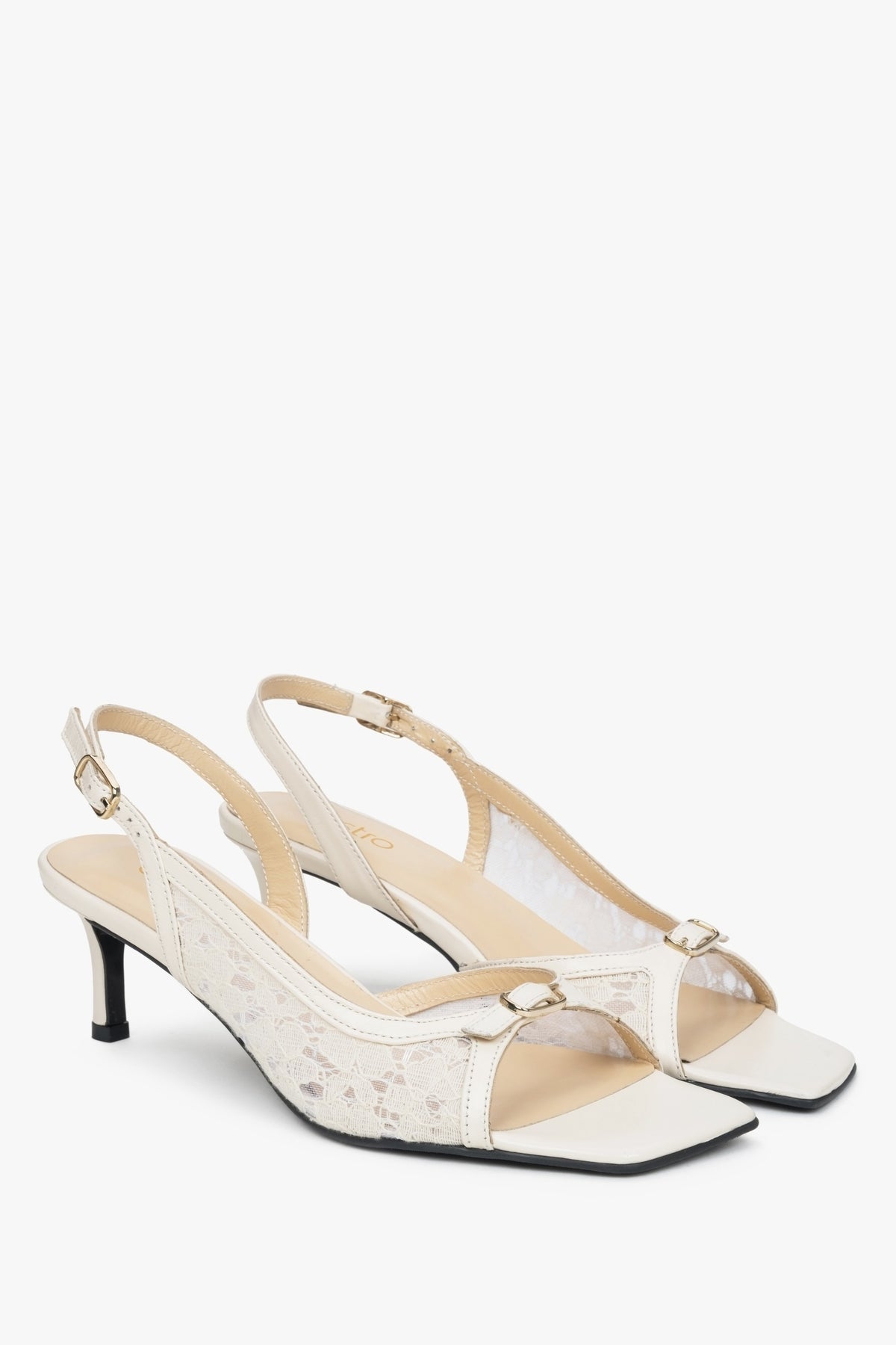 White slingback sandals with decorative lace and a heel.