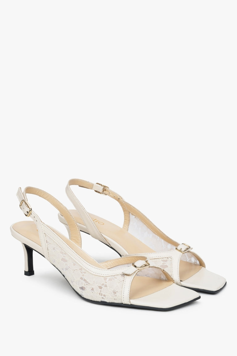 White slingback sandals with decorative lace and a heel.