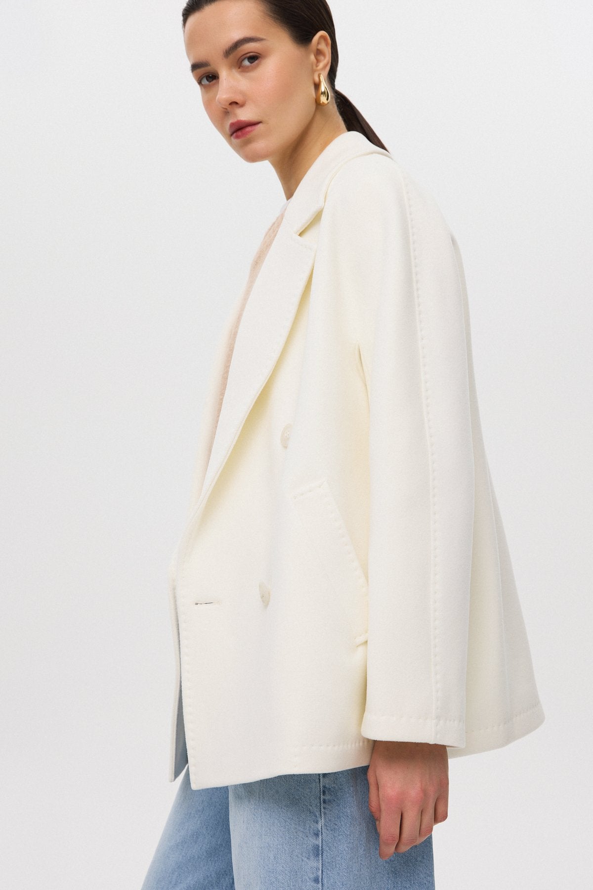 A short, double-breasted women's coat in white Estro.