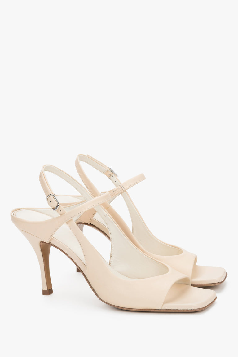 Elegant nude stiletto sandals featuring a stabilizing strap and luxury leather finish.