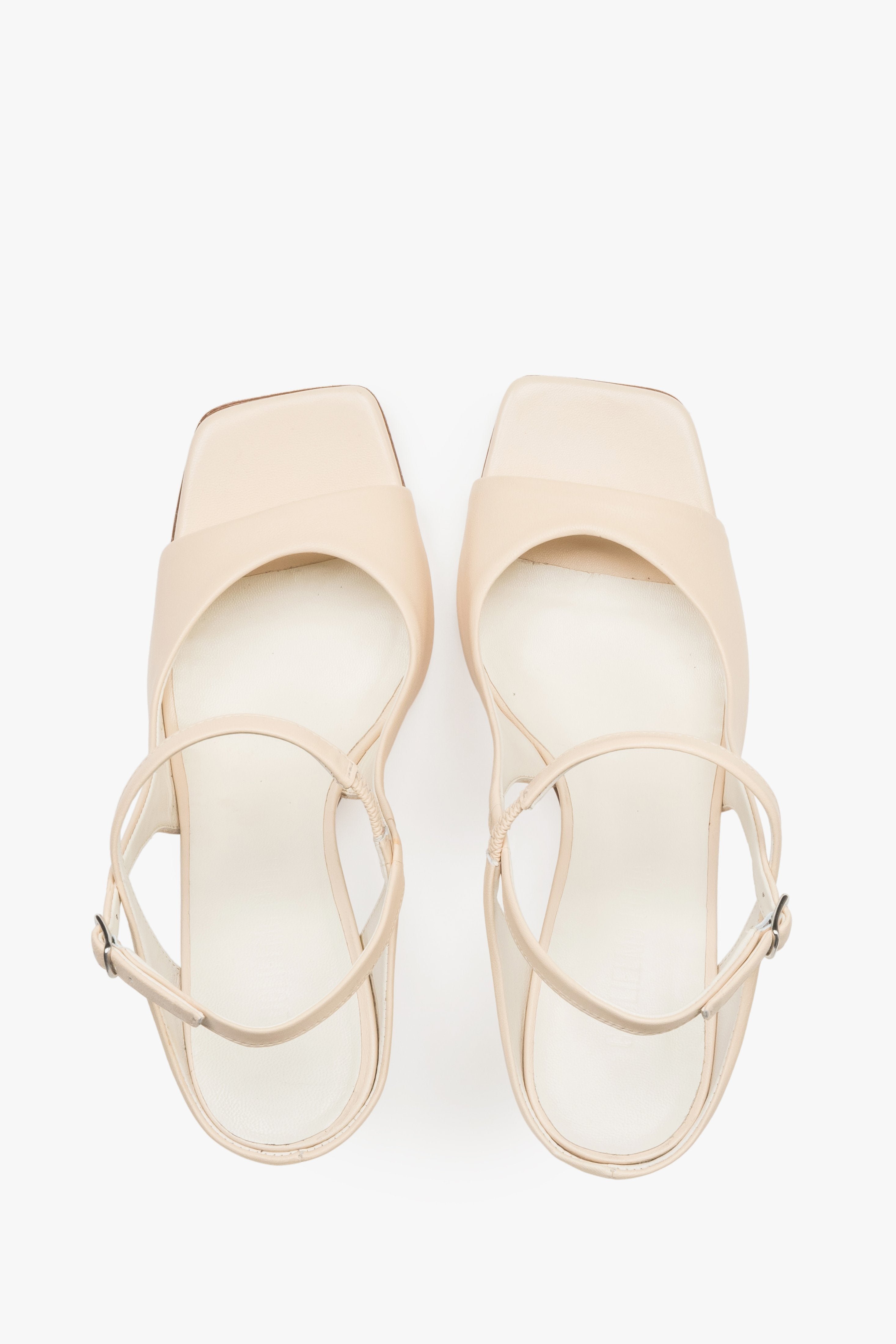 Close-up of the additional stabilizing strap and premium leather texture on beige sandals.