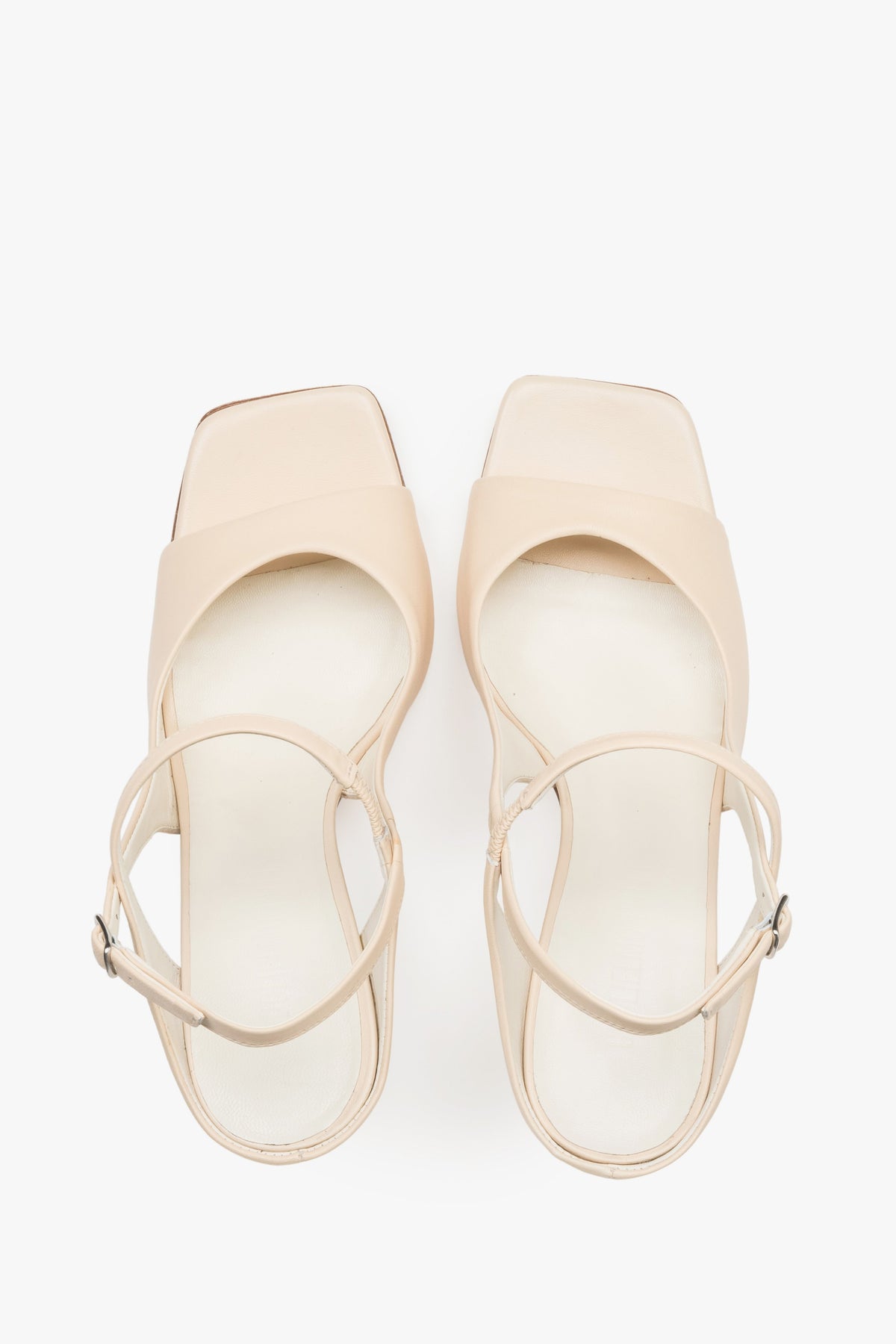 Close-up of the additional stabilizing strap and premium leather texture on beige sandals.