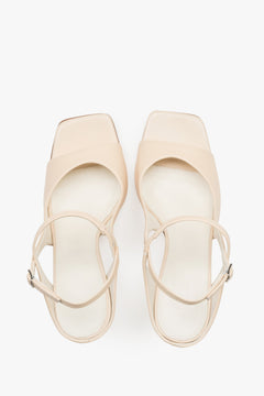 Close-up of the additional stabilizing strap and premium leather texture on beige sandals.