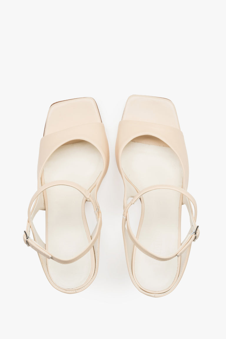 Close-up of the additional stabilizing strap and premium leather texture on beige sandals.