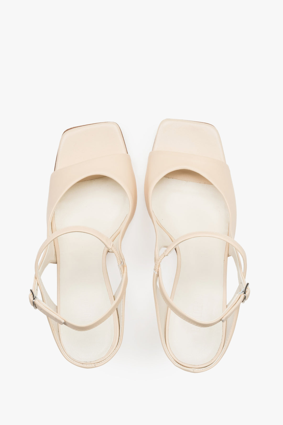 Close-up of the additional stabilizing strap and premium leather texture on beige sandals.