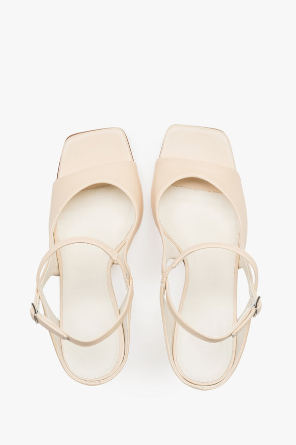 Close-up of the additional stabilizing strap and premium leather texture on beige sandals.