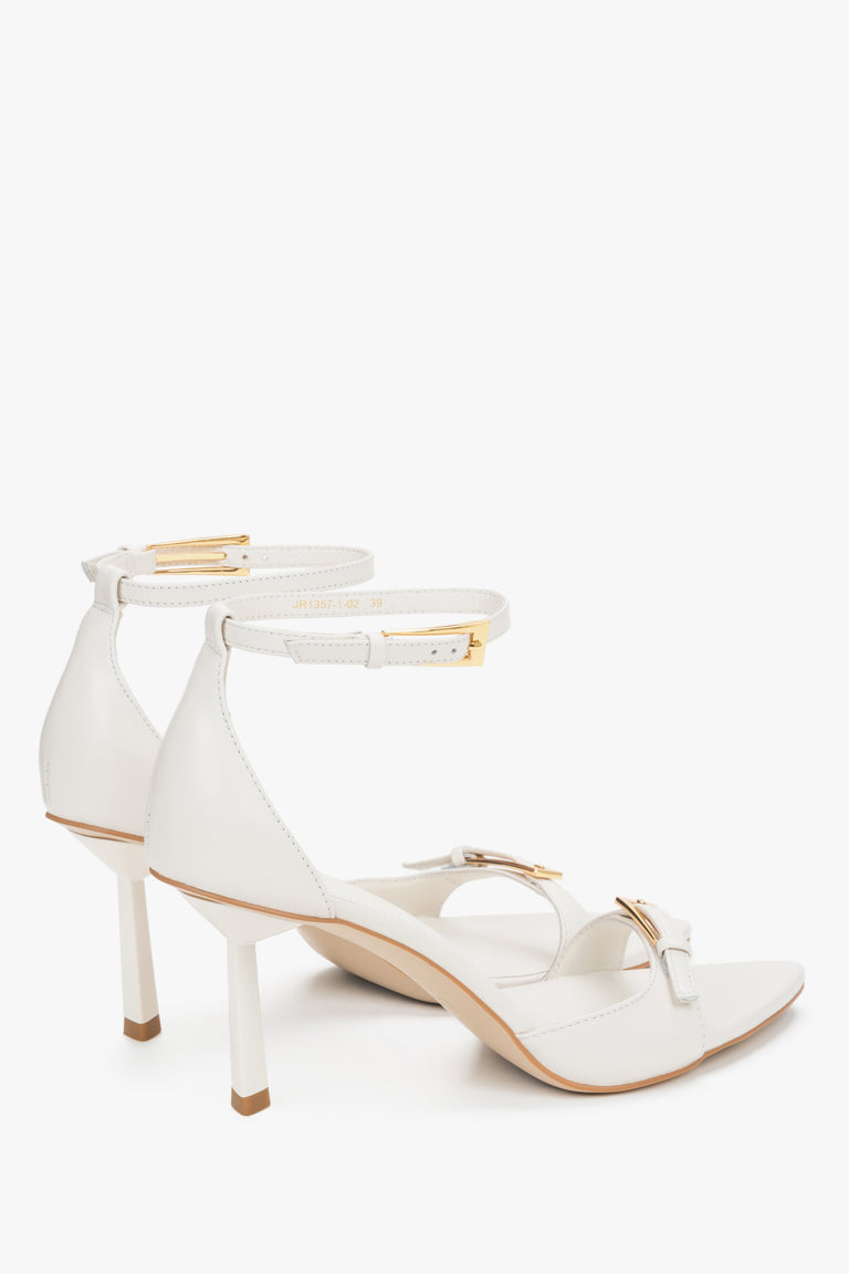 Detail view of decorative buckles on beige leather Estro sandals.