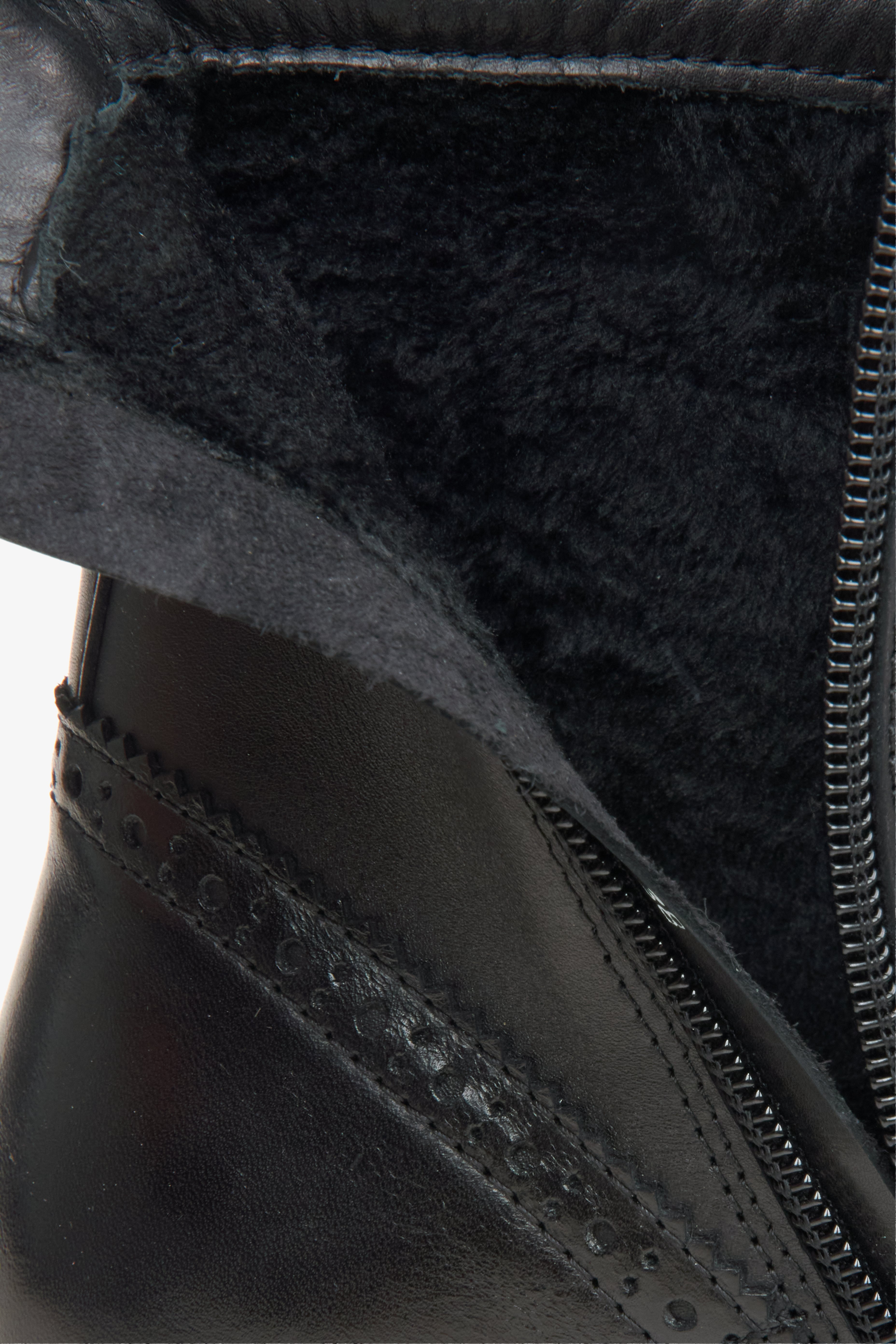 A black leather lace-up ankle boot with a side zipper, decorative brogue detailing, and a chunky lug sole.
