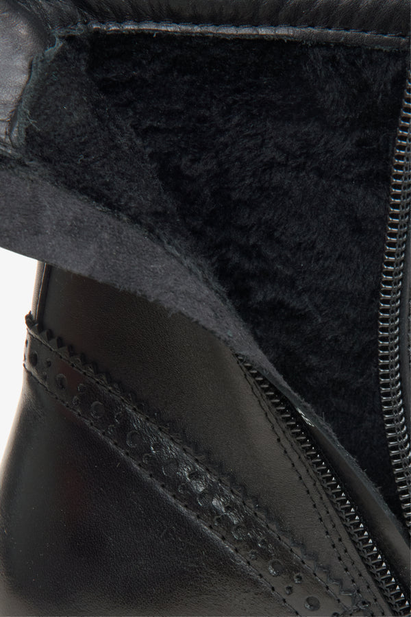 A black leather lace-up ankle boot with a side zipper, decorative brogue detailing, and a chunky lug sole.