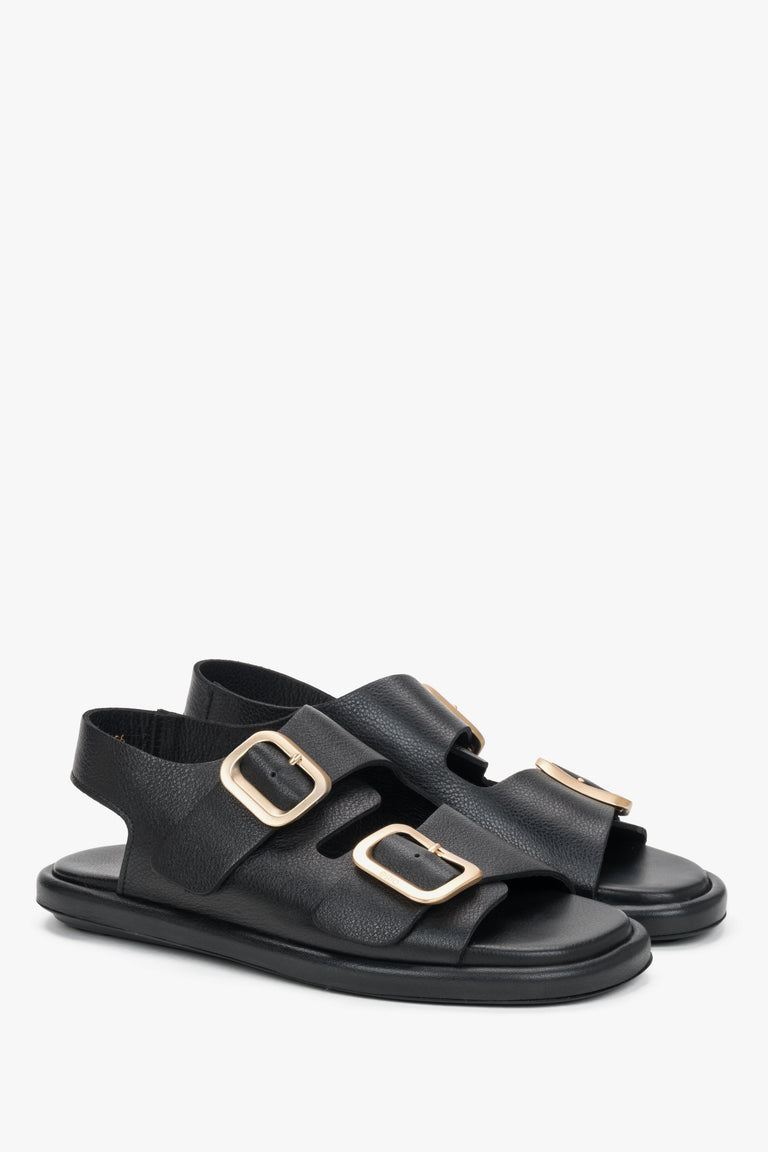 Black women’s flat sandals with adjustable gold-tone buckles.