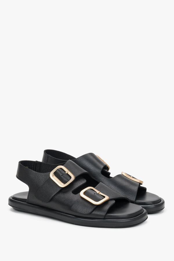 Black women’s flat sandals with adjustable gold-tone buckles.