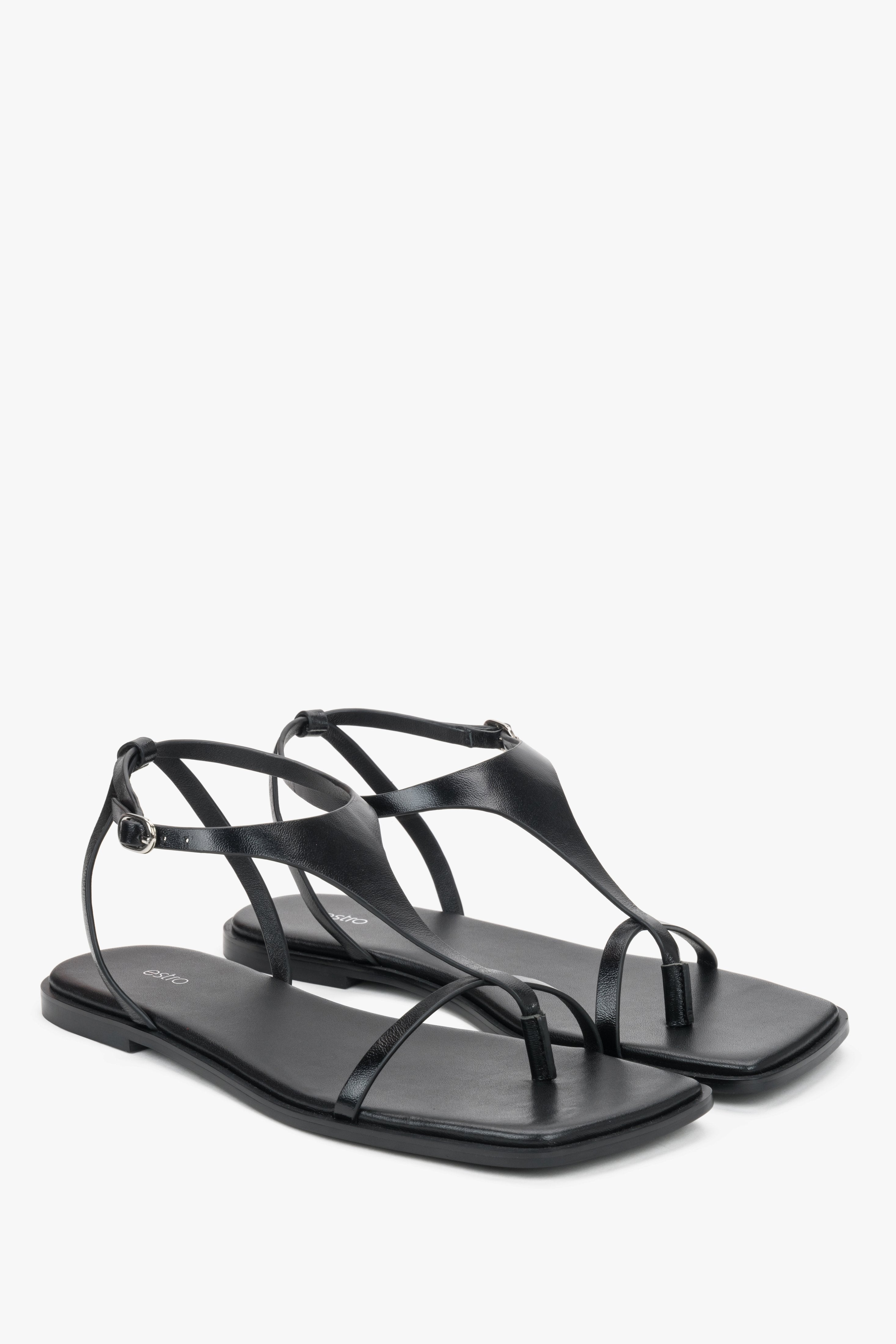 Black flat sandals with a square toe and a toe-post strap.