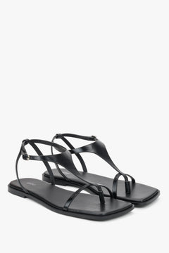 Black flat sandals with a square toe and a toe-post strap.