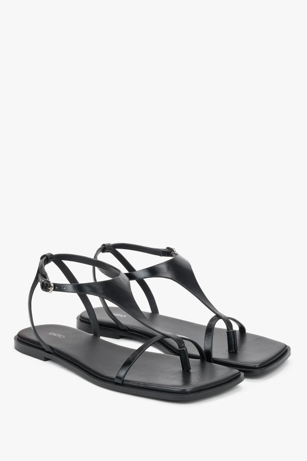 Black flat sandals with a square toe and a toe-post strap.