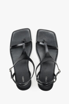 Women’s black flat sandals with a square toe and toe-post strap by Estro.