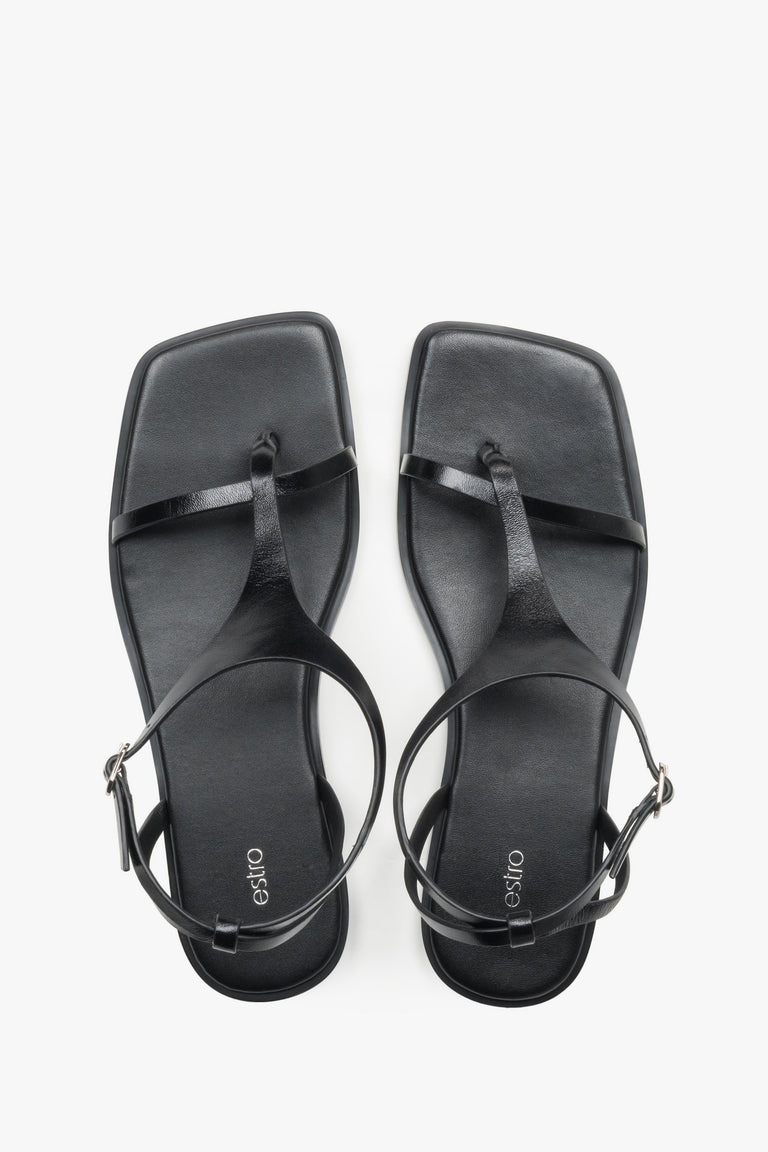 Women’s black flat sandals with a square toe and toe-post strap by Estro.