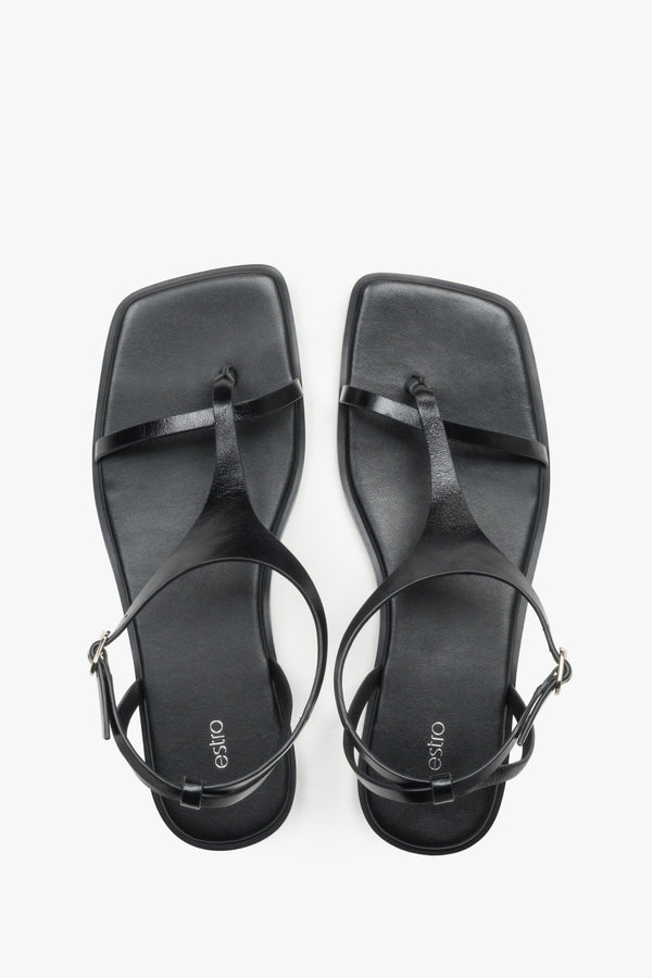 Women’s black flat sandals with a square toe and toe-post strap by Estro.