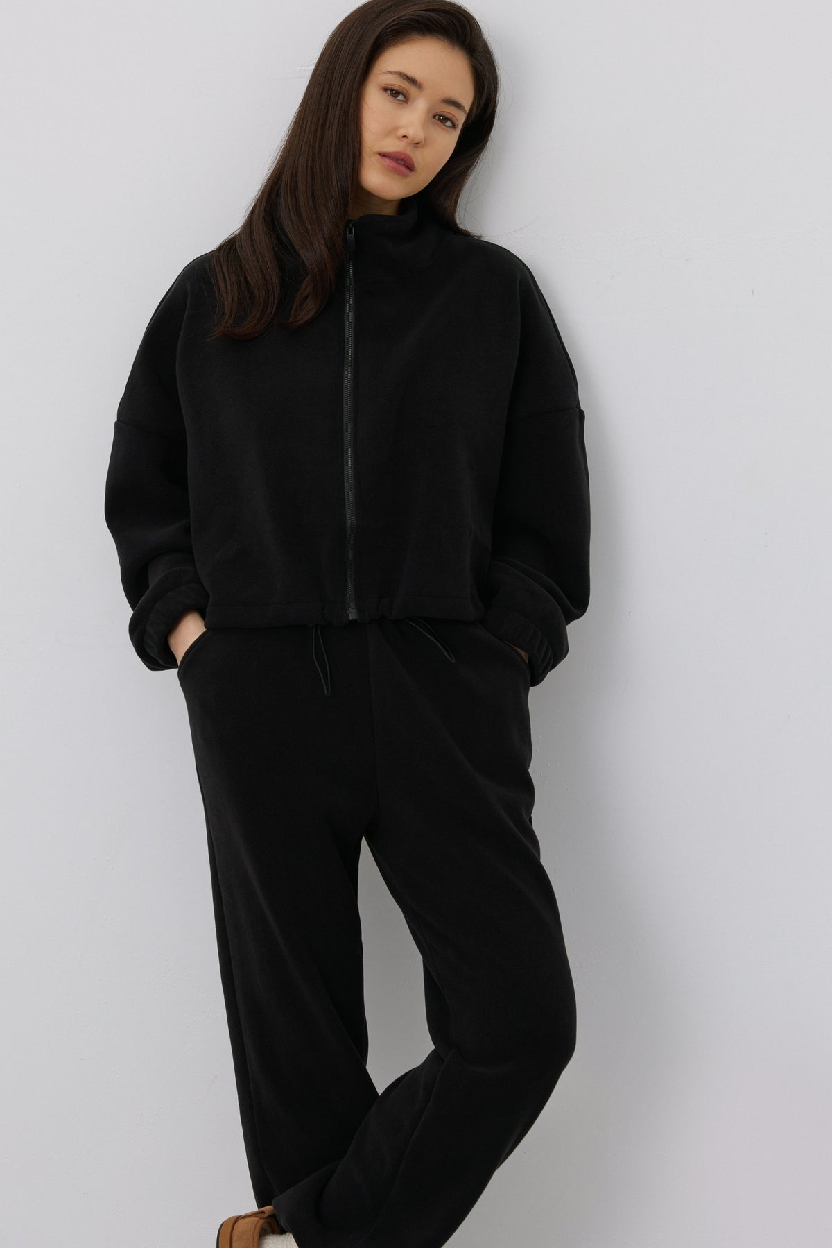 Women's black fleece tracksuit set Estro - close-up view highlighting the cozy fleece texture, hood detailing, and subtle finish.