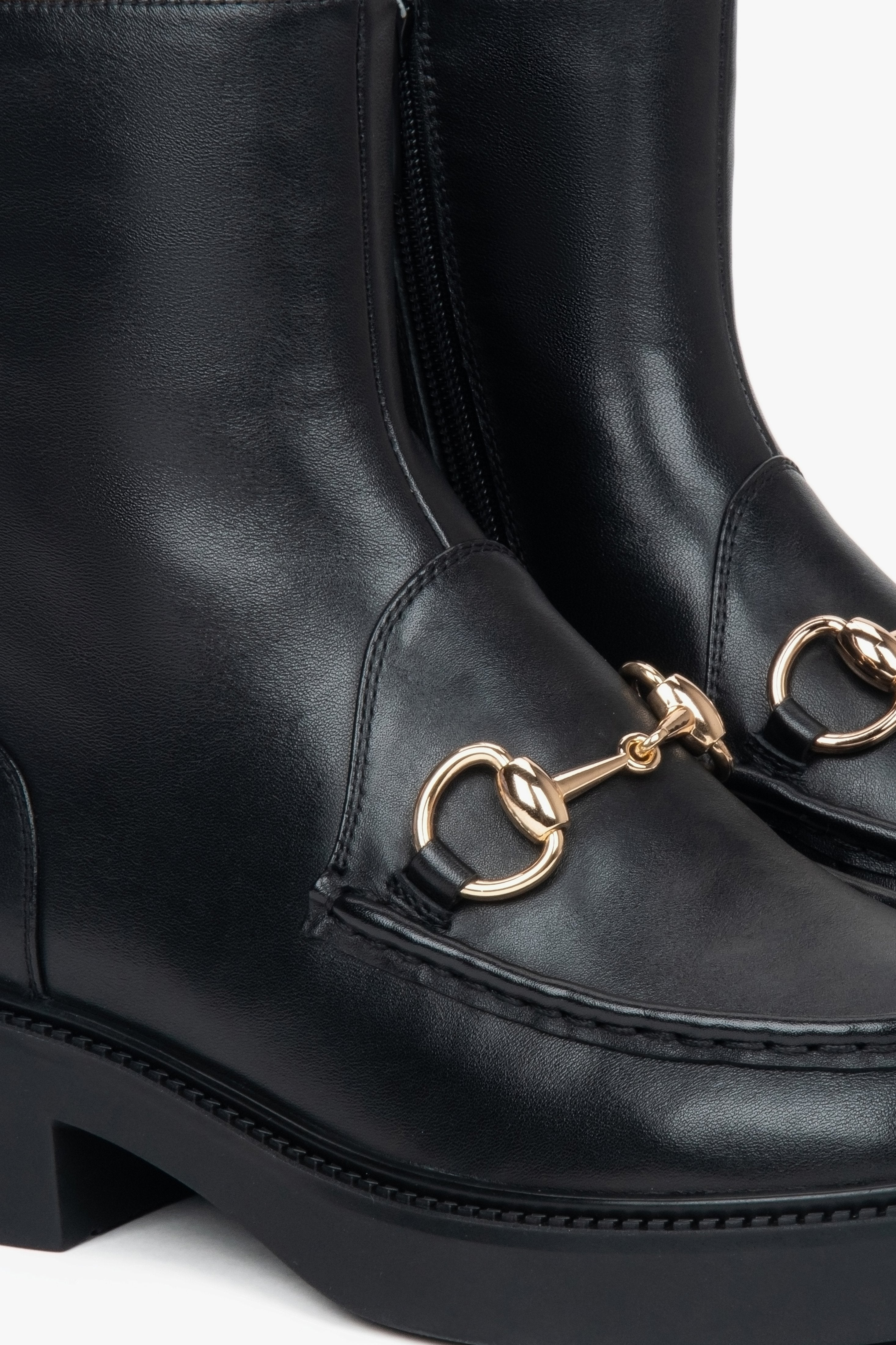 Black women’s leather ankle boots by Estro with a decorative buckle – close-up of details.
