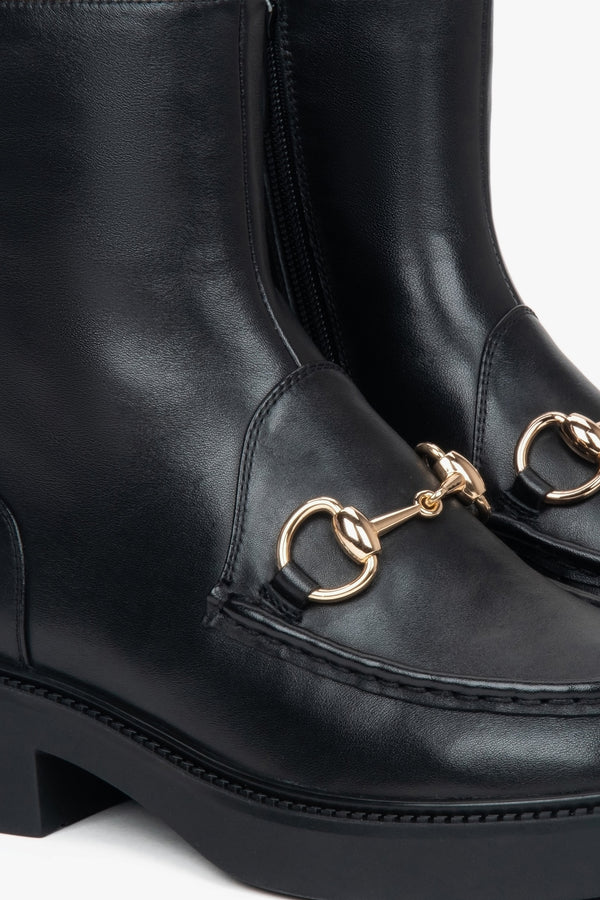 Black women’s leather ankle boots by Estro with a decorative buckle – close-up of details.