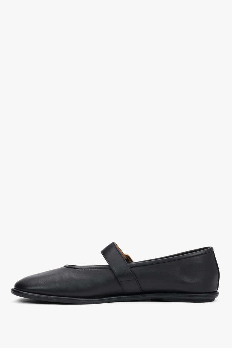 A profile shot of the black leather ballet flats highlighting the slim, flat rubber sole and the elegant positioning of the adjustable ankle strap.