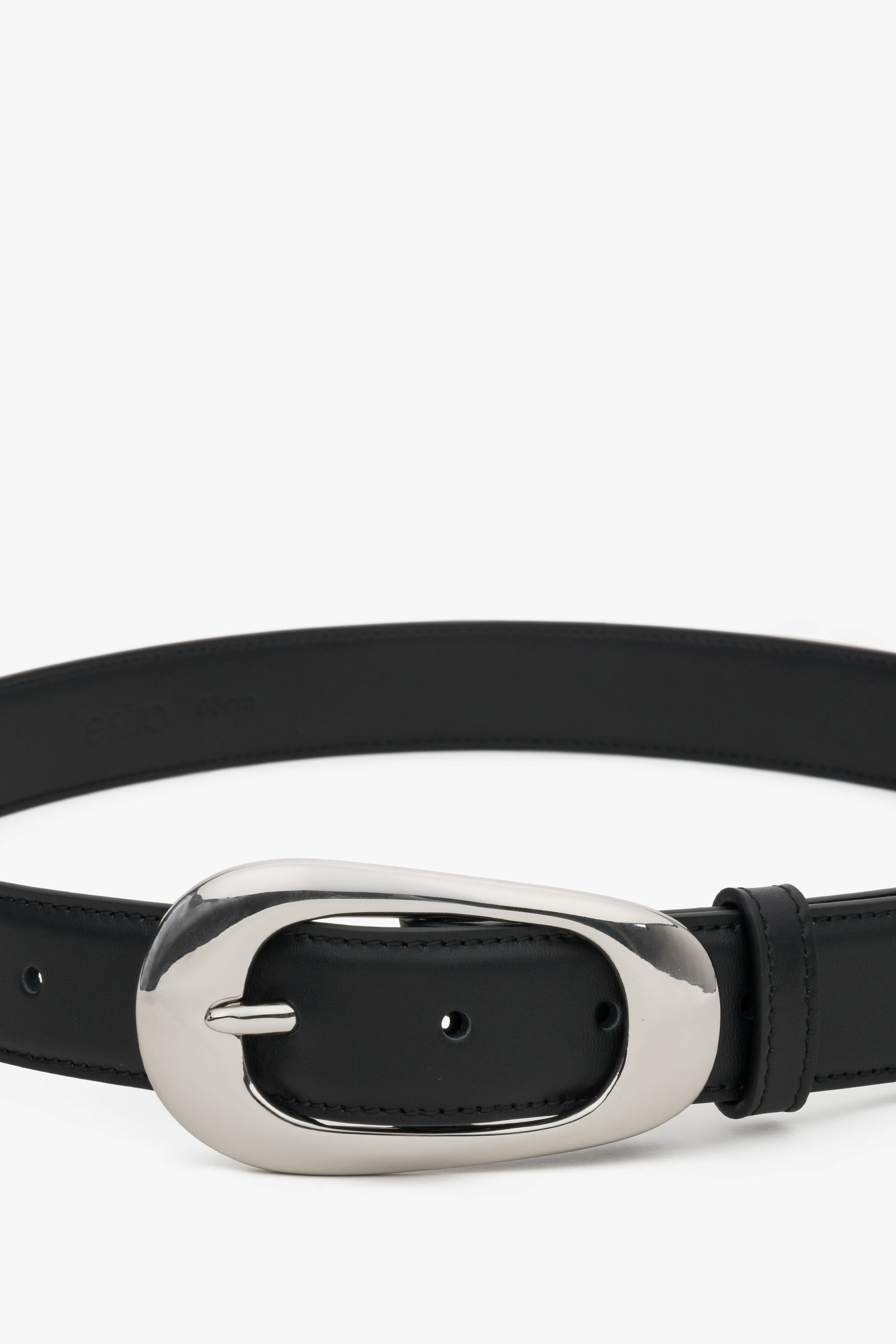 Close-up of the large oval buckle on a black leather belt.