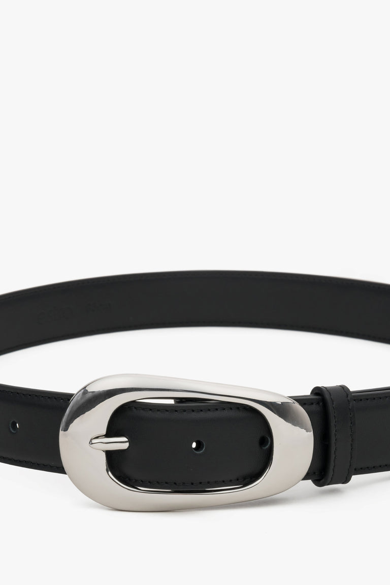 Close-up of the large oval buckle on a black leather belt.
