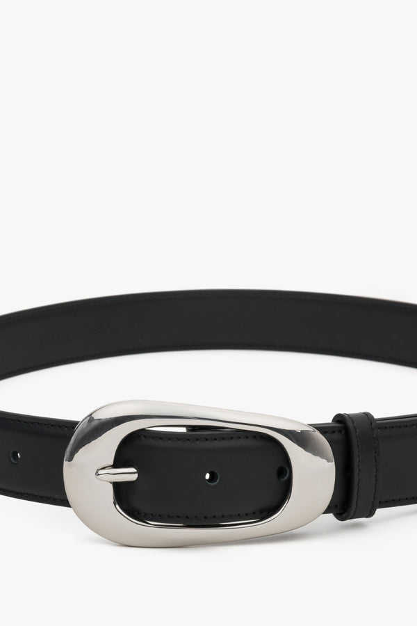 Close-up of the large oval buckle on a black leather belt.