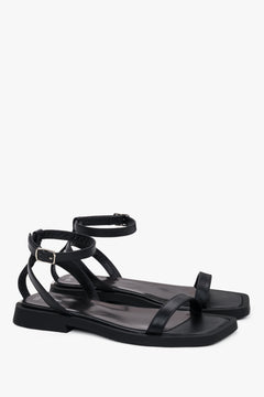Side view of women’s black flat sandals with delicate thin straps.