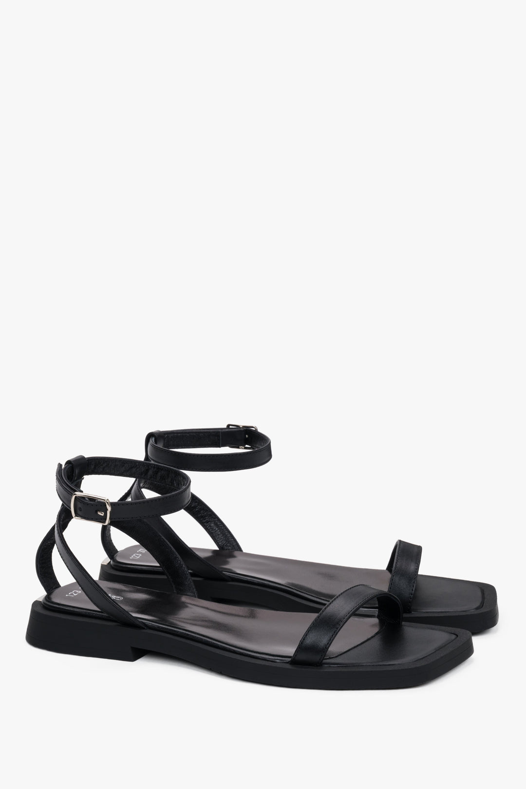 Side view of women’s black flat sandals with delicate thin straps.