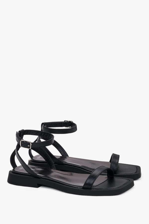 Side view of women’s black flat sandals with delicate thin straps.