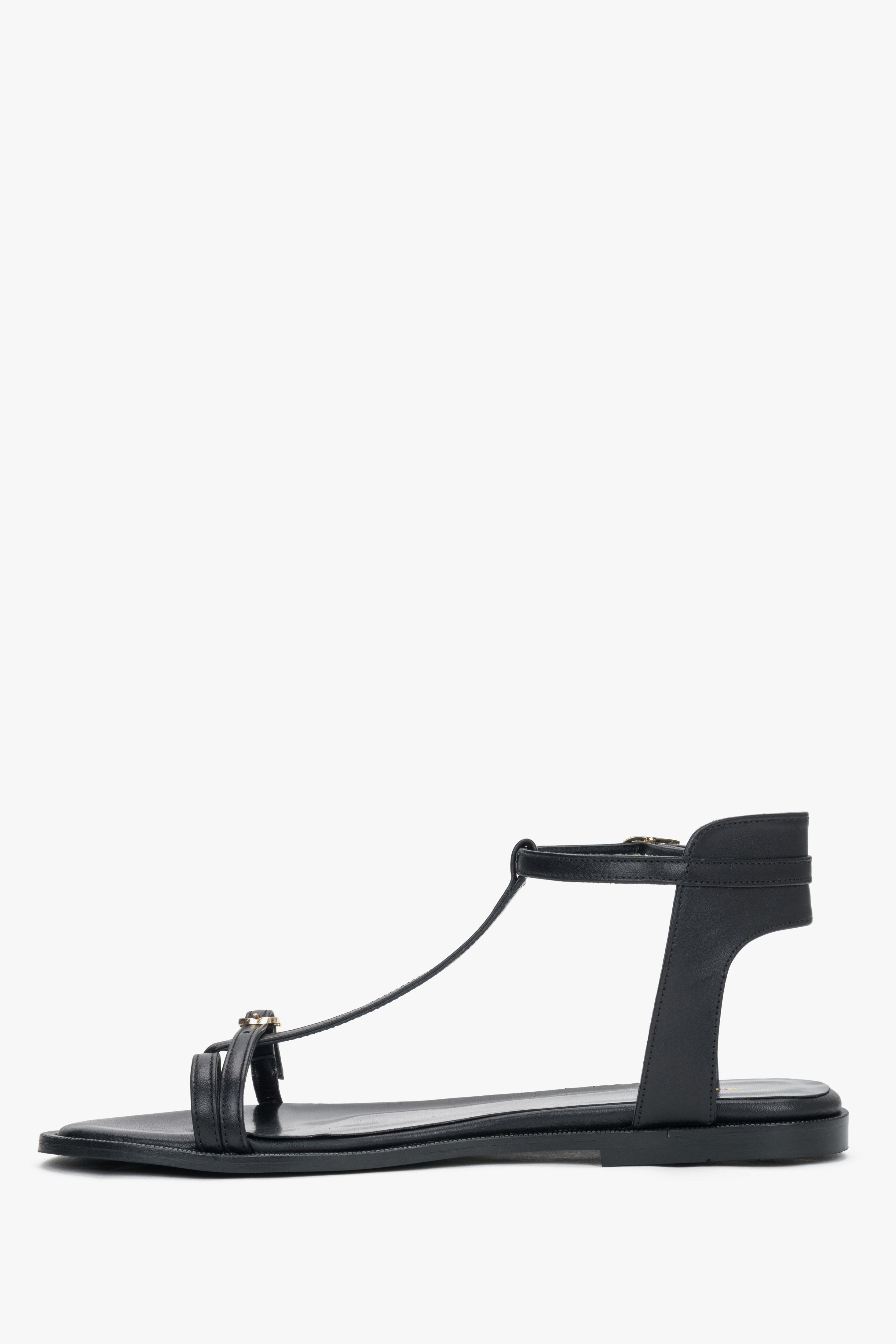 Side view of women's black leather flat sandals with T-strap
