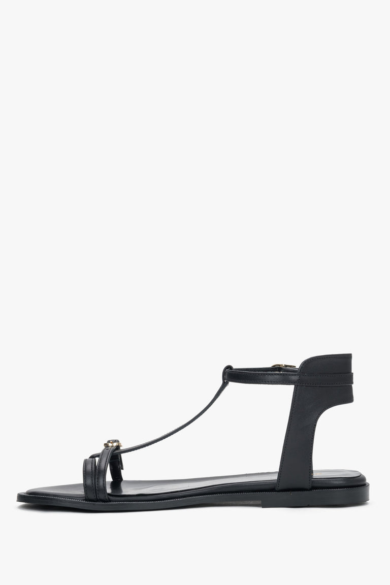 Side view of women's black leather flat sandals with T-strap