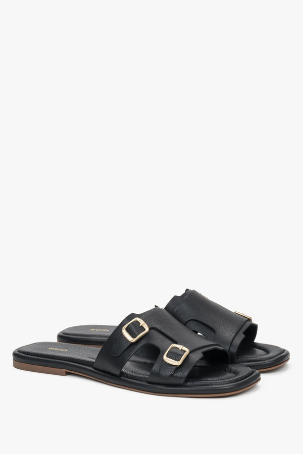 A close-up shot focusing on the smooth, deep black leather texture and the polished brilliance of the adjustable golden buckles.