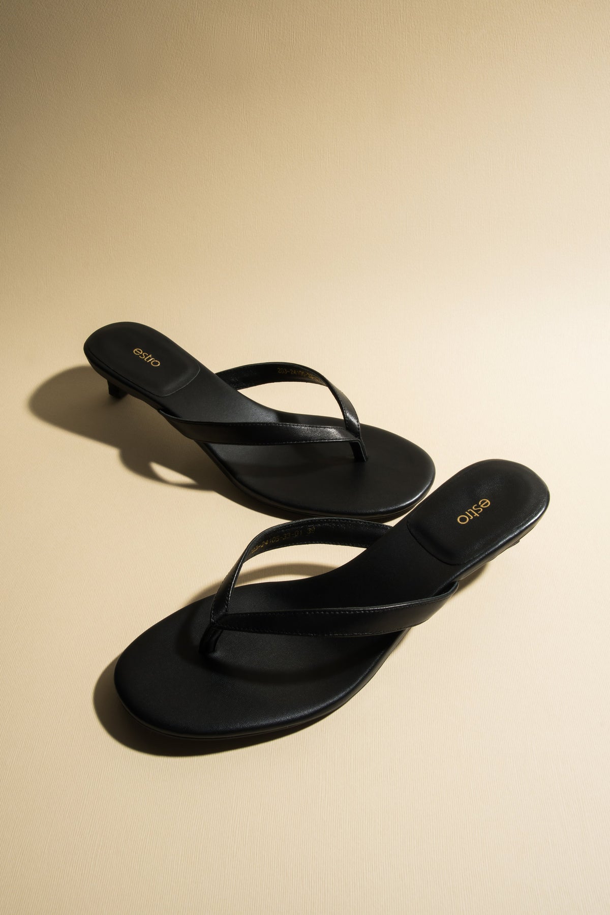 Women’s black leather thong sandals with a low heel by Estro.