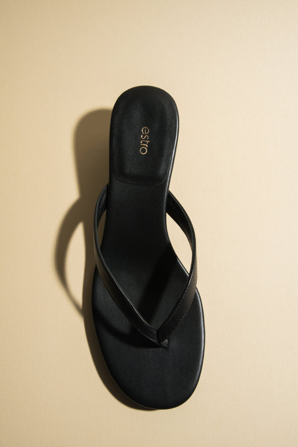 Black leather thong sandals with a low heel by Estro.