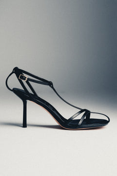 Women's black leather high heel sandals styled with Estro packaging