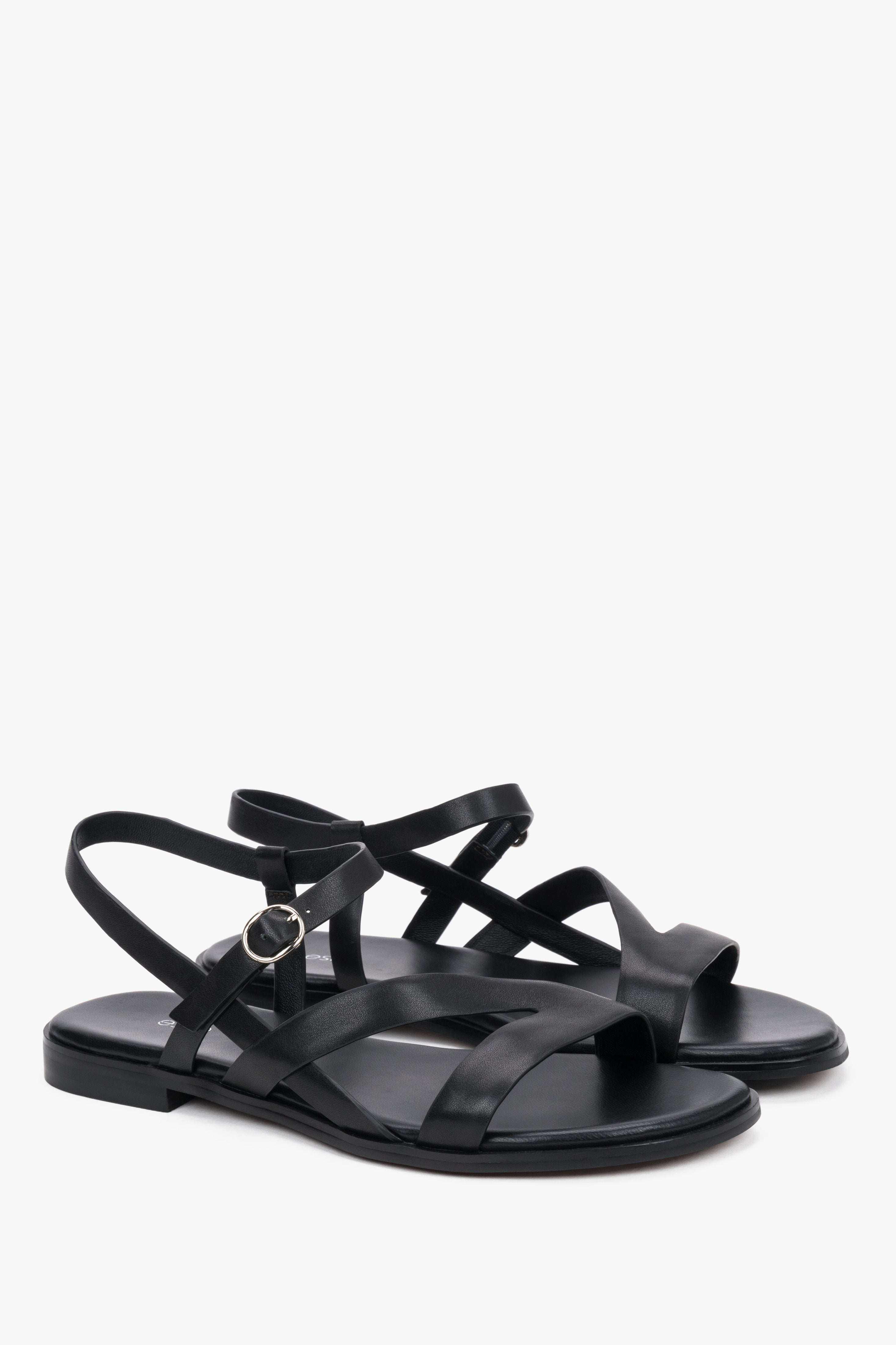 Black women’s leather sandals with crisscross straps and a flat sole.