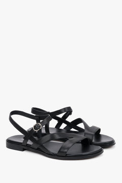 Black women’s leather sandals with crisscross straps and a flat sole.