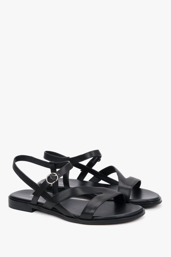 Black women’s leather sandals with crisscross straps and a flat sole.