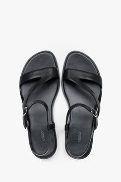 Women’s black Estro leather sandals with crisscross straps and a flat sole.