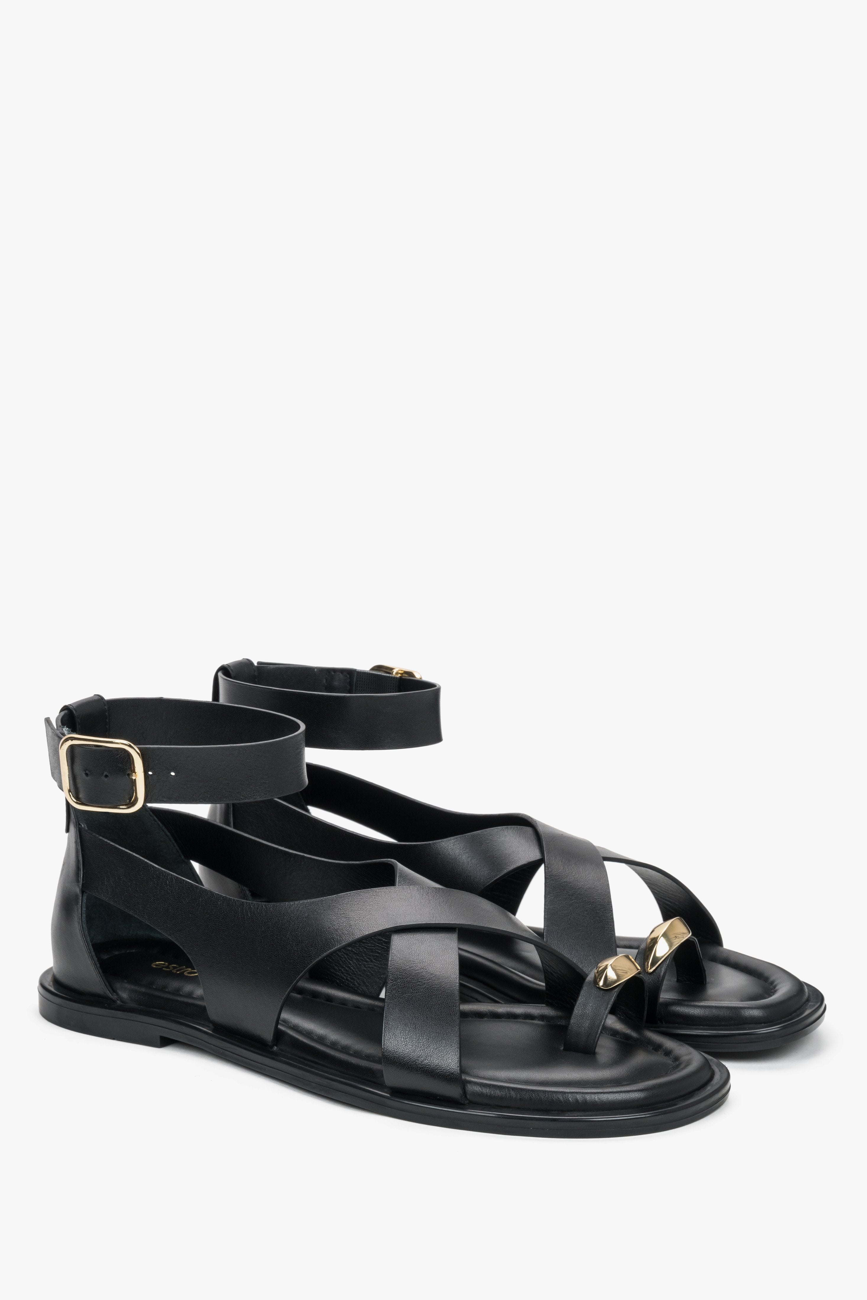 Black leather women’s sandals with a gold toe ring detail.