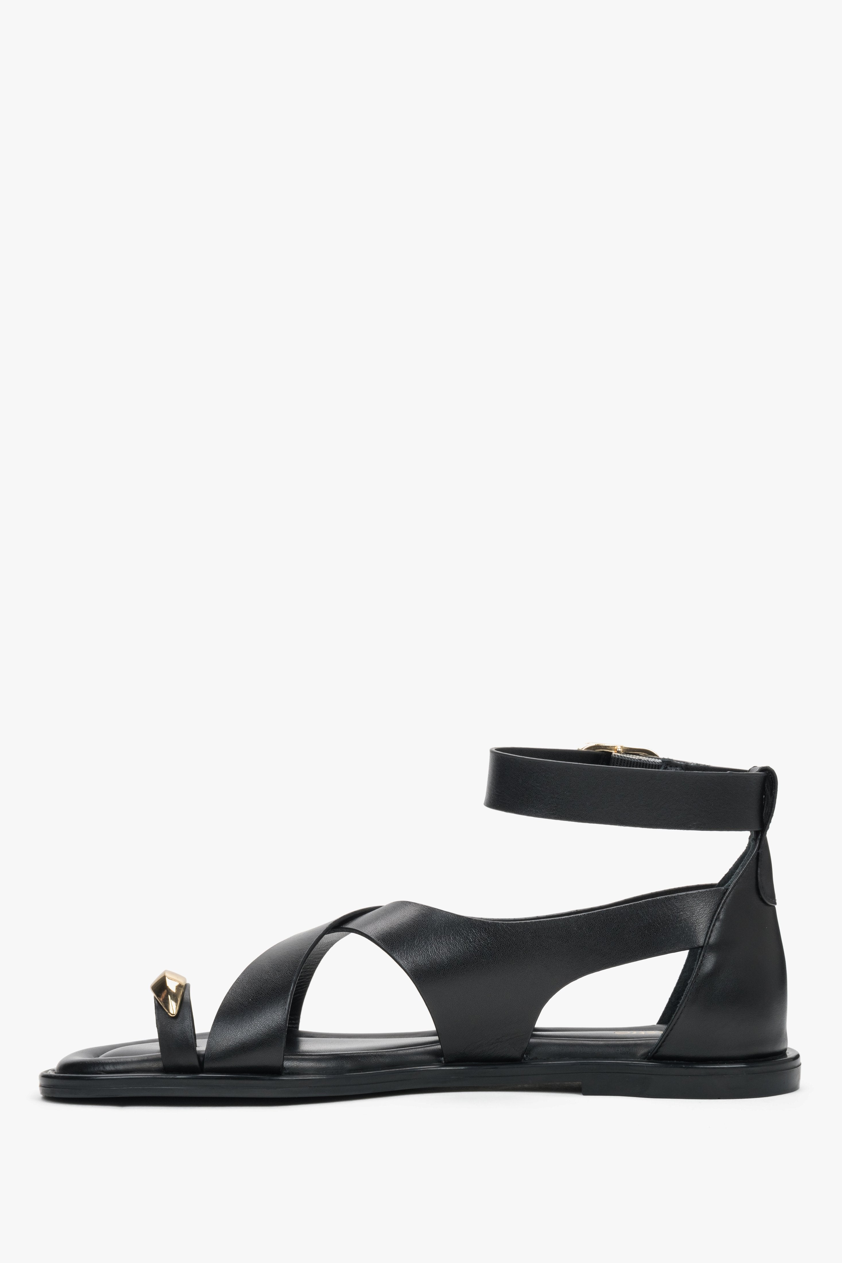 Black leather women’s Estro sandals with a gold toe ring detail - side view. 
