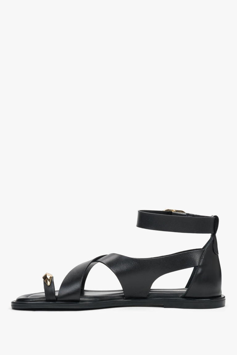 Black leather women’s Estro sandals with a gold toe ring detail - side view. 